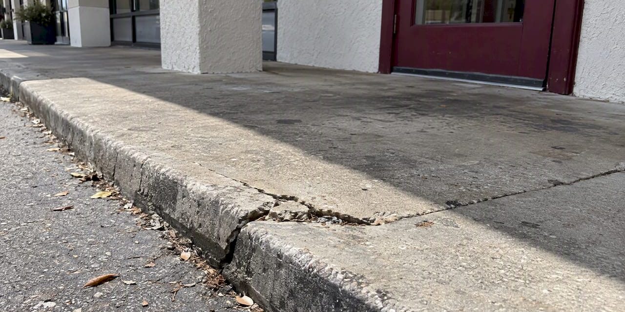 Cracked curb hidden by walkway shadow